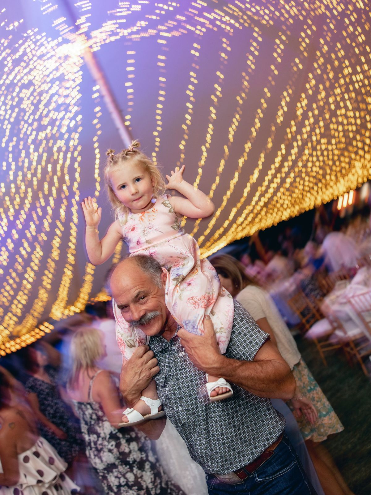 Grandfather with a child on his shoulders under the lights