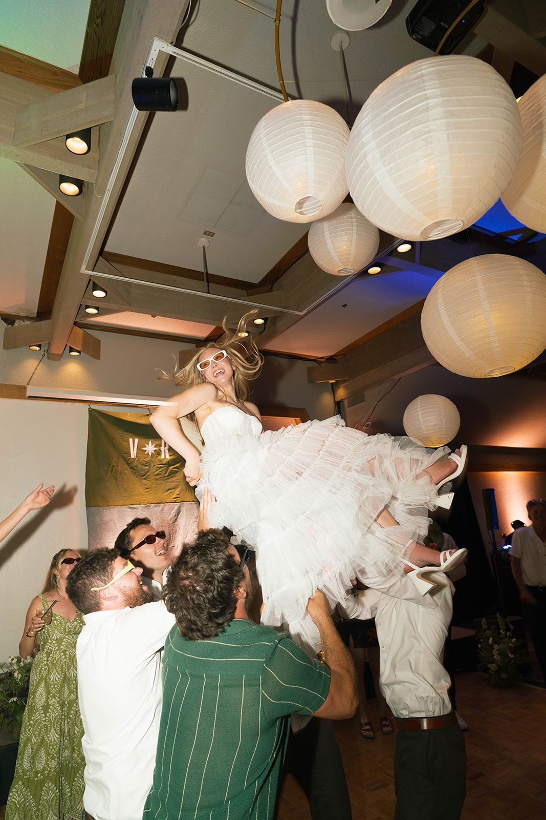 Bride lifted by the party under paper lanterns