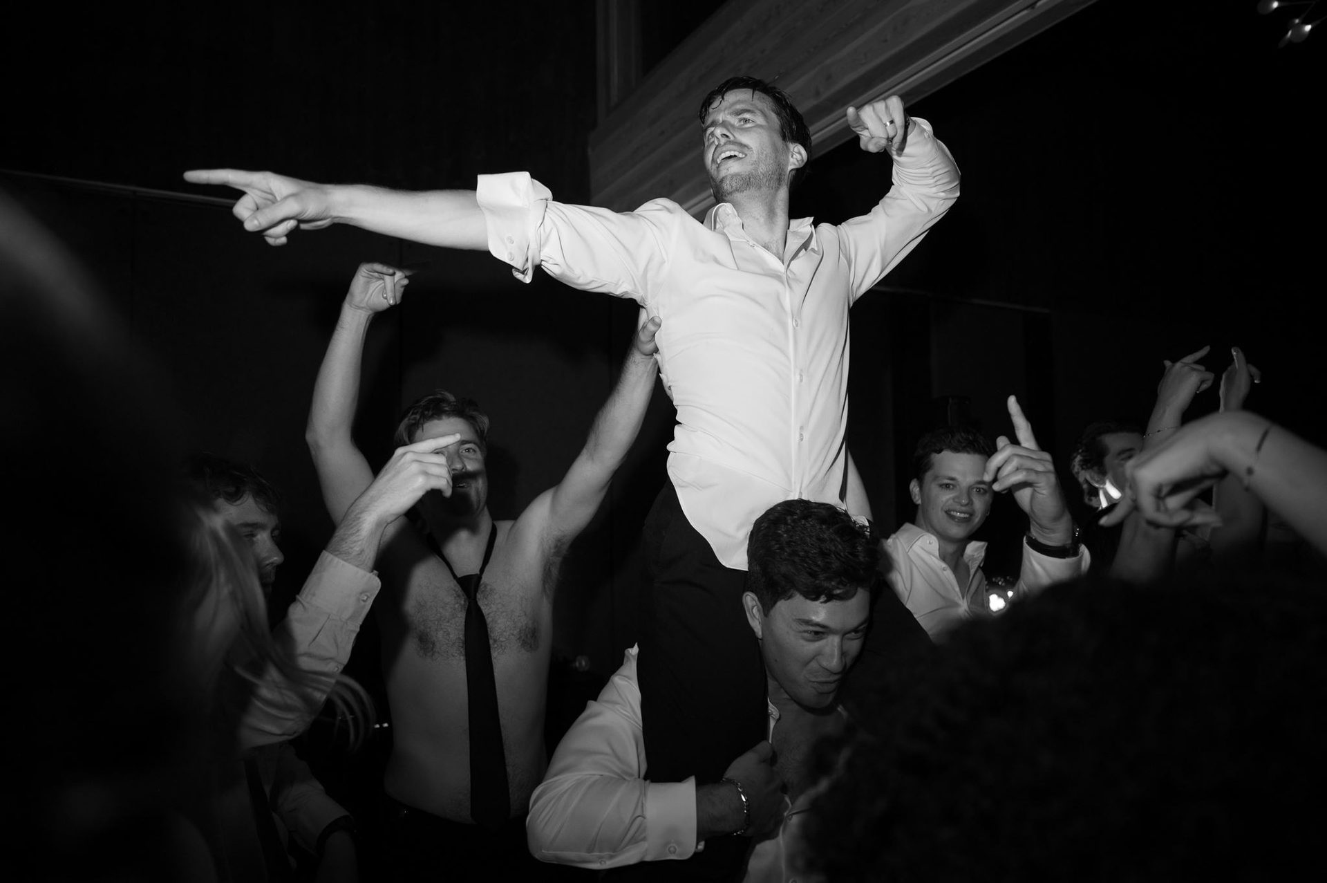 Groom pointing from the crowd's shoulders