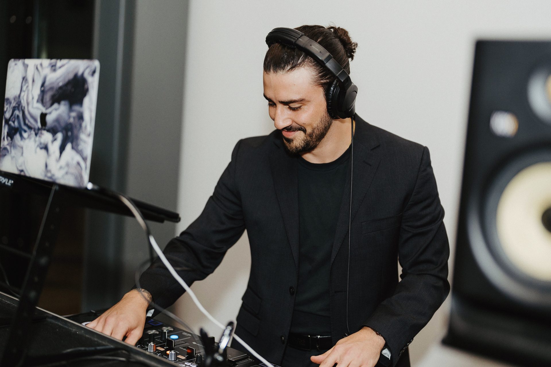 WHIPLSH mixing live in a black suit, headphones on