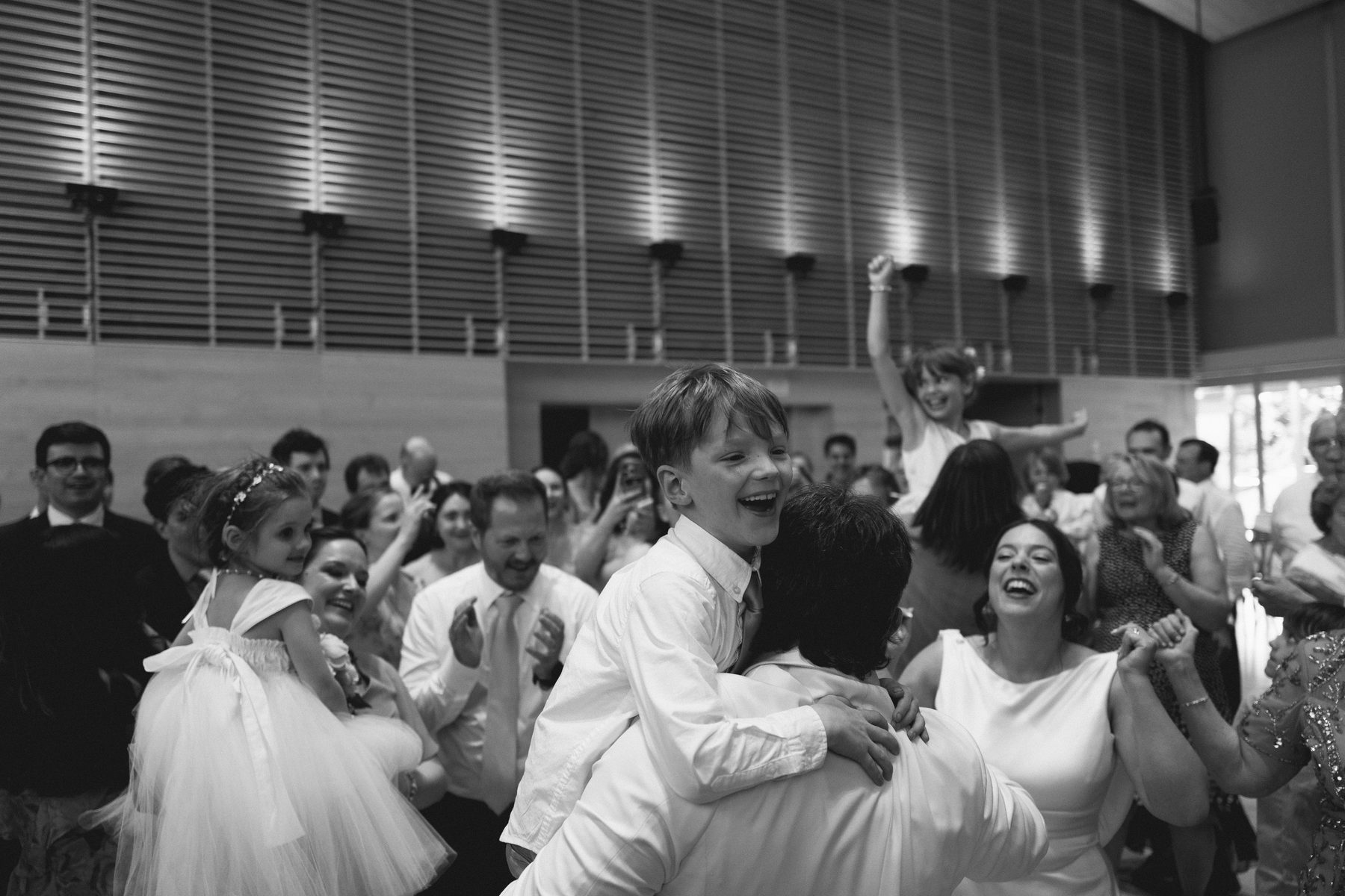 A kid on dad's shoulders, laughing through the party