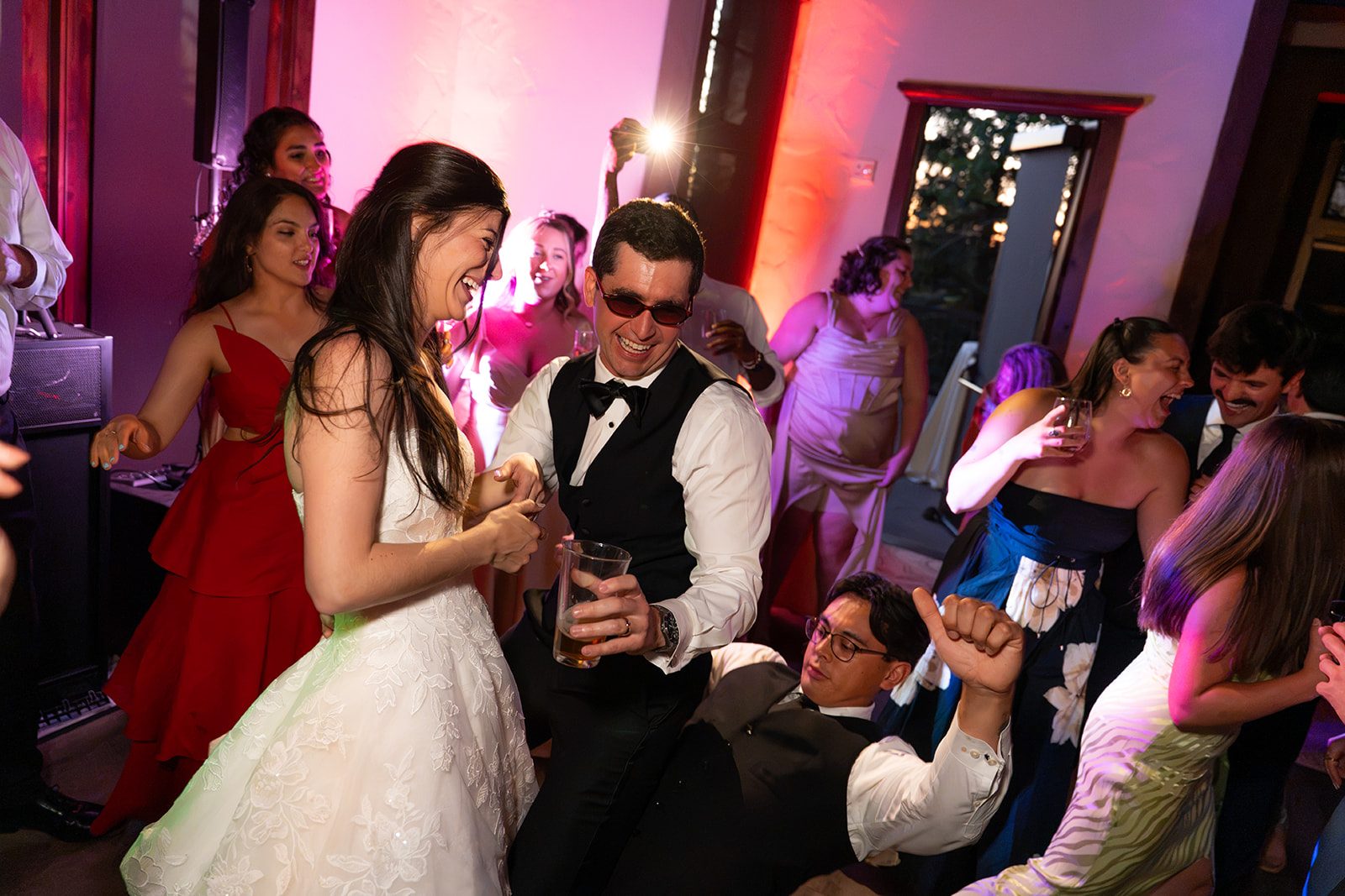 Packed dance floor under red and pink uplights
